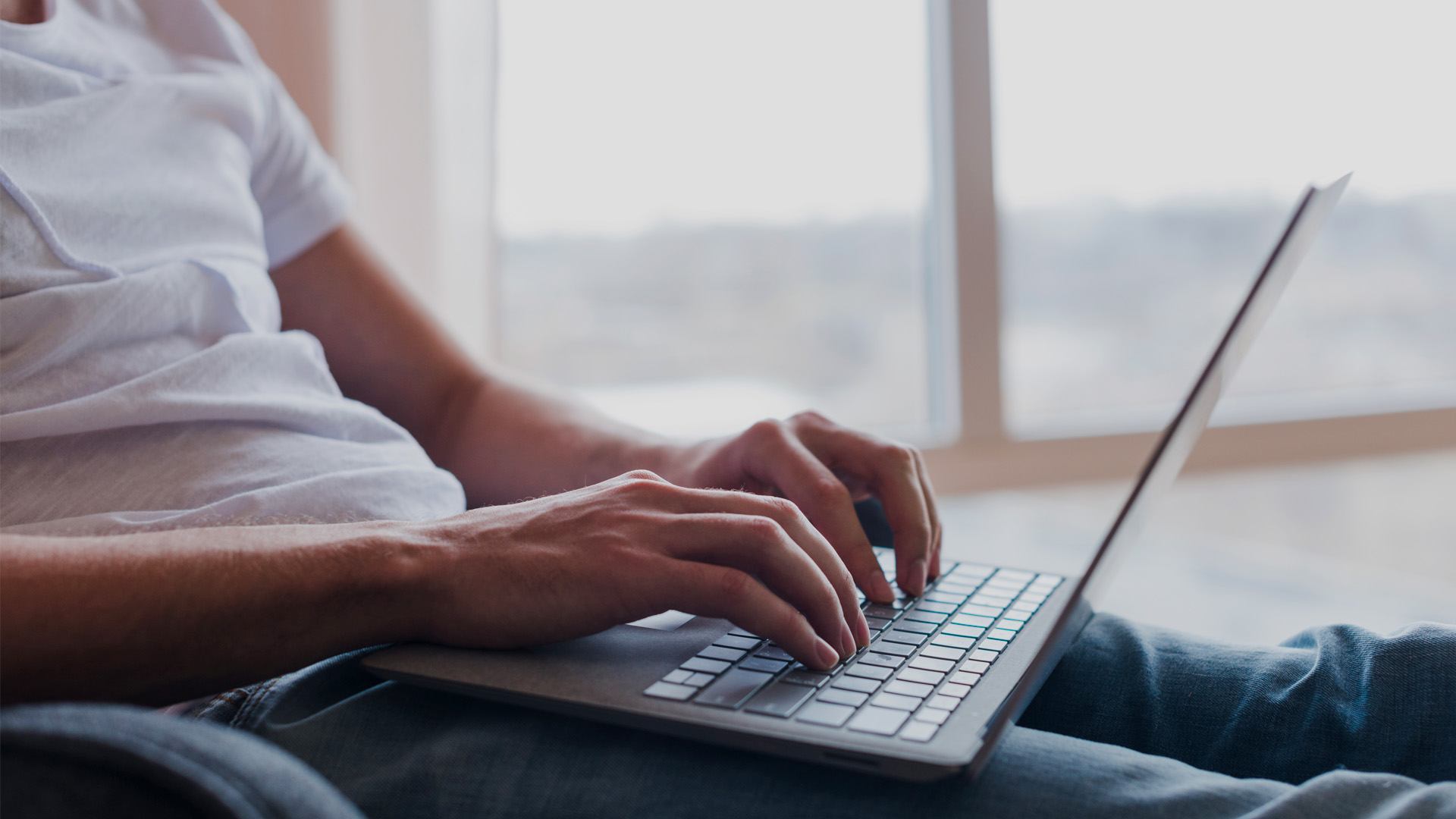 man-sitting-chair-typing-laptop-near-window (1)